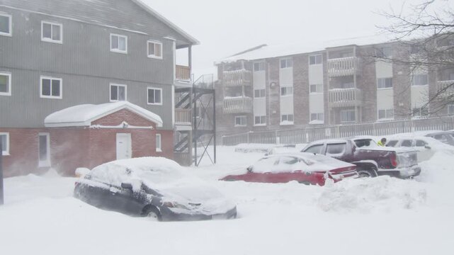 During a classic Nor'easter snowstorm in Nova Scotia, a heavy dump of snow transforms yards and driveways into a sea of white. Residents begin clearing thick snow around vehicles and paths.