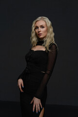Fototapeta premium Woman in black outfit poses confidently against a dark background at a studio photoshoot