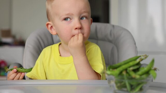 Little kid eats fresh green peas. 4R