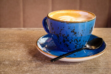 Cup of cappuccino on a wooden table in a cozy café. Warm natural light and relaxing morning atmosphere. 