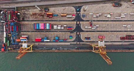 Top down rows of colorful shipping containers and gantry cranes at busy industrial port during daytime, illustrating global logistics and freight transportation. High angle aerial drone view flight - Powered by Adobe