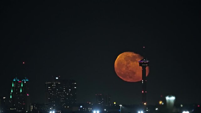 Vibrant Moon Rise Behind Tower of Americas and San Antonio Skyline with Elevator Descending Through Atmospheric Distortion