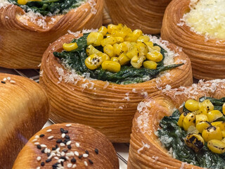 Spinach and corn Danish pastry with cheese shavings. Fusion of colors, textures, and taste in gourmet bakery presentation.