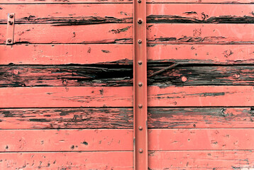 Old red painted wooden door with metal hinges.