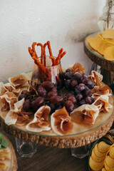 Buffet table serving grapes, prosciutto ham, and grissini sticks