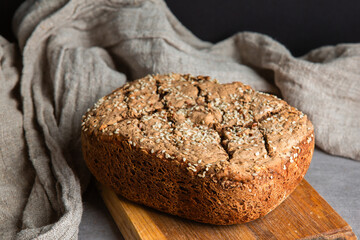 Fresh whole grain bread with sesame seeds on cutting board
