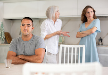 Obraz premium Elderly woman during family quarrel with married couple in kitchen