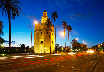 The historic 'Torre del oro' tower illuminated on the shoreline of the Quadalquivir River in Seville at dusk