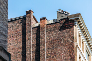 Brick walls and chimneys of old downtown buildings under clear blue sky in Montreal