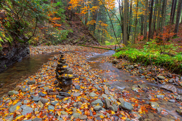 Rocky mountain stream with stone cairn and autumn foliage near Parashka trail by Skole town in Lviv region, Ukraine