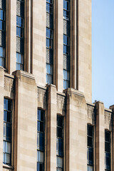 Detail of the Art Deco Aldred Building facade on Place d'Armes in Old Montreal, showing vertical stone lines and ornamented windows
