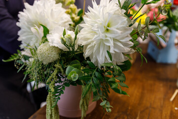 Vase of white flowers sits on a wooden table