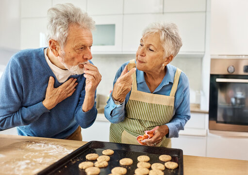 Portrait of grandparents and grandchildren having fun together preparing and eating baked dessert food in kitchen at home