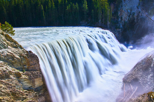 Powerful Waterfall Flowing Over Rocky Cliff With Lush Forest In Background - Powered by Adobe