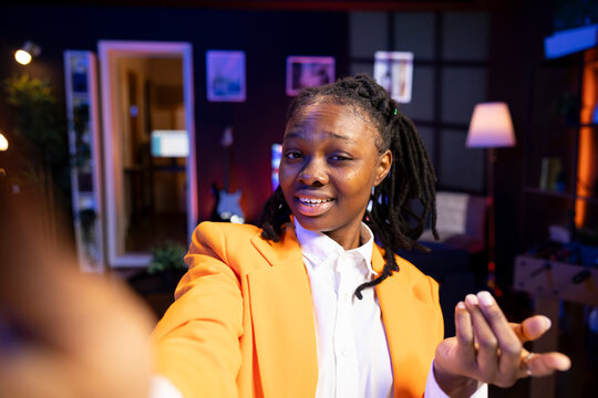 Content creator using smartphone to do live broadcast for subscribers showing her new home studio design. Media star films herself for audience using mobile phone camera in apartment