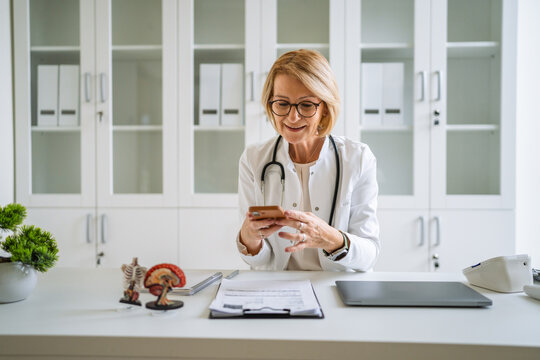 Smiling doctor using smart phone for healthcare consultation
