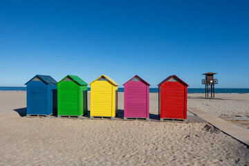 Colorful beach huts on cullera sand with lifeguard tower