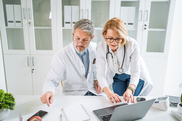 Medical team collaborating discussing patient data on laptop
