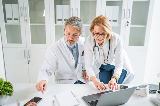 Medical team collaborating discussing patient data on laptop