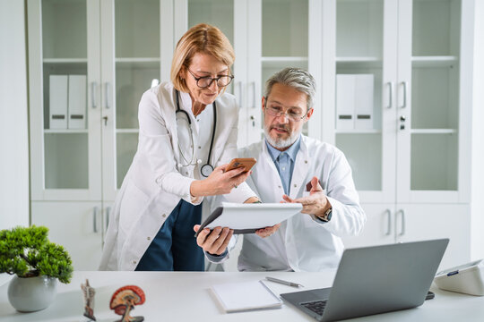 Medical professionals collaborating on smart phone reviewing patient data