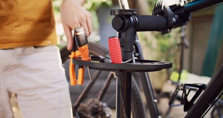 Close-up shot of caucasian hand arranging different professional equipment for summer bike maintenance. Detailed view of person organizing various expert bicycle work tools in home yard.