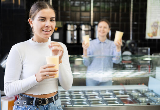 Near bar, girl drinks tonic bubble tea through straw. Client is tasting beverage with unusual taste