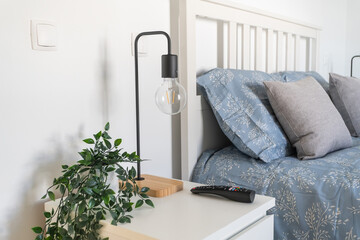 This cozy bedroom showcases a modern design with soft blue bedding, stylish pillows, a bedside...