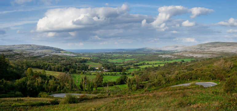 View from Corkscrew Hill on Burren mountains, Atlantic ocean and Galway bay. Popular tourist area. Travel and tourism. Cloudy sky. Stunning Irish landscape with green fields. Panorama image.