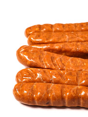 A row of top quality hot dogs are sitting on a white background. The hot dogs are covered in a brown glaze and are arranged in a neat row. Simple product made to highest standard.