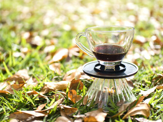 Drip coffee on the autumn morning grass