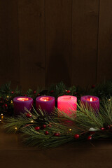 Four advent candles lit for the fourth week of advent on a black background with copy space