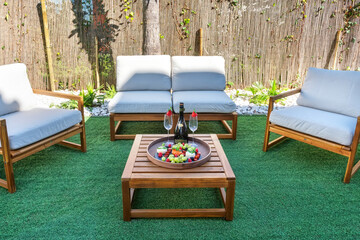A cozy outdoor seating area features wooden furniture with cushions, drinks in glasses, and a platter of fresh fruit, creating a welcoming atmosphere for relaxation
