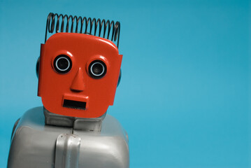 Red retro toy windup robot against blue backdrop