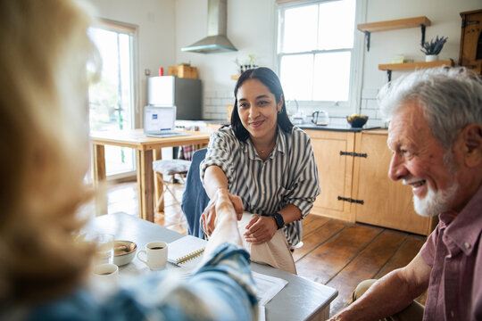 Young adult woman and senior man smiling during handshake at home