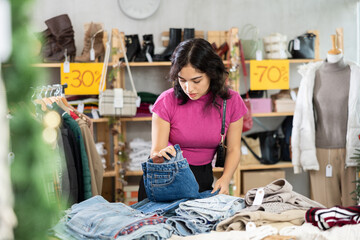 Asian woman chooses jeans trousers in a clothing store before Christmas