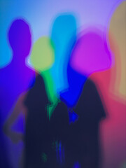 People silhouettes blending with colorful neon light blur