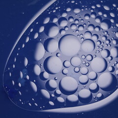 Una toma de cerca de un fondo abstracto de varias burbujas en agua y aceite en movimiento en un fondo de color azul oscuro  con algo de desenfoque