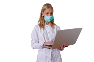 Medical professional woman in a white lab coat and protective face mask working on a laptop, standing with a transparent background
