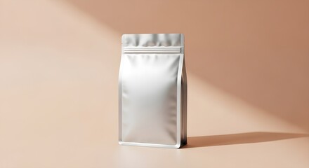 A silver package stands on a peach surface with a shadow cast by the sunlight