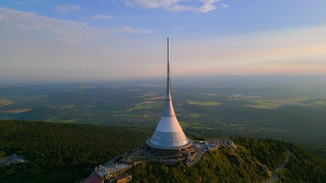 Witness breathtaking sunset vistas from Jested Mountain, featuring the iconic tower and hotel in Liberec, Czechia. Drone shots showcase the surrounding landscape in golden hues.