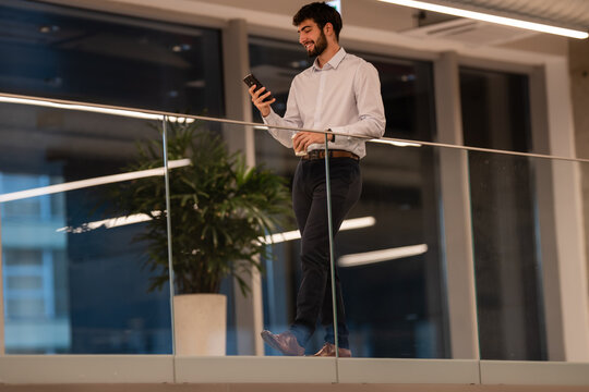 Young businessman walking, using smartphone, having coffee break - Powered by Adobe