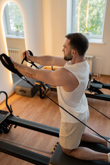 Kneeling pulley exercise, practicing on reformer pulley row focusing on shoulder control