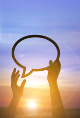 Silhouette hands holding speech bubble at sunset, freedom of expression concept