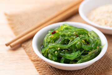 Wakame seaweed salad with sesame seed in a bowl on wooden background