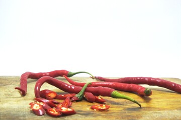 The fresh curly red chilies or capsicum annuum on an old wooden cutting board