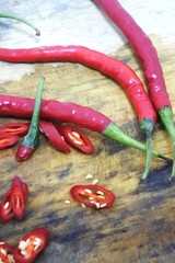 The fresh curly red chilies or capsicum annuum on an old wooden cutting board