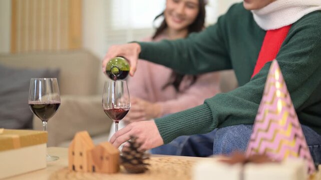 Asian couple pouring red wine celebrating christmas at home