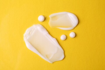 Samples of moisturizing creams on yellow background, flat lay