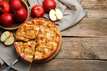 Delicious homemade pie and apples on wooden table, flat lay. Space for text