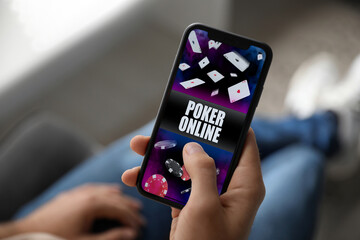Man playing online poker on mobile phone indoors, closeup